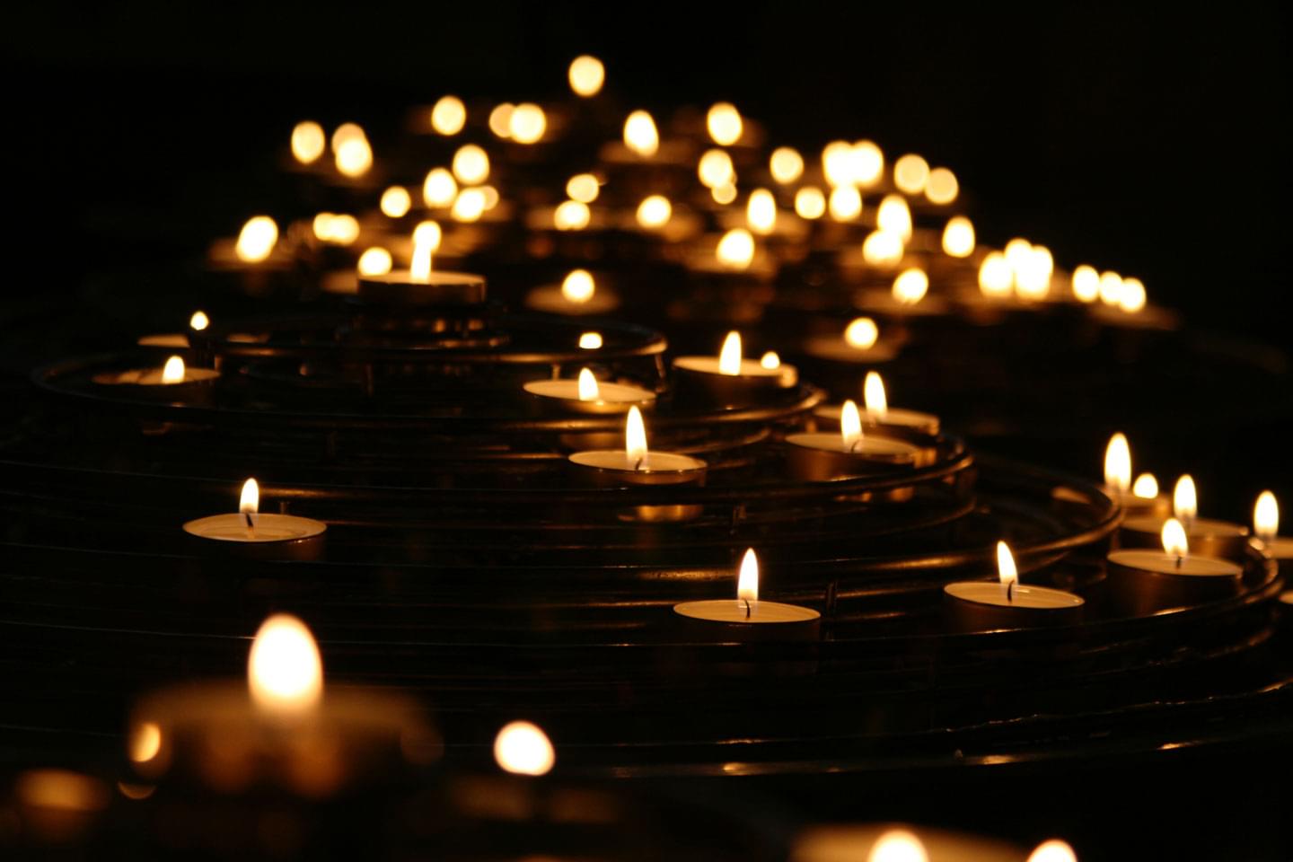 Viele Teelichter im Dunkeln ergeben ein Meer aus Kerzen, Kerzenlicht als Zeichen der Andacht und Trauer