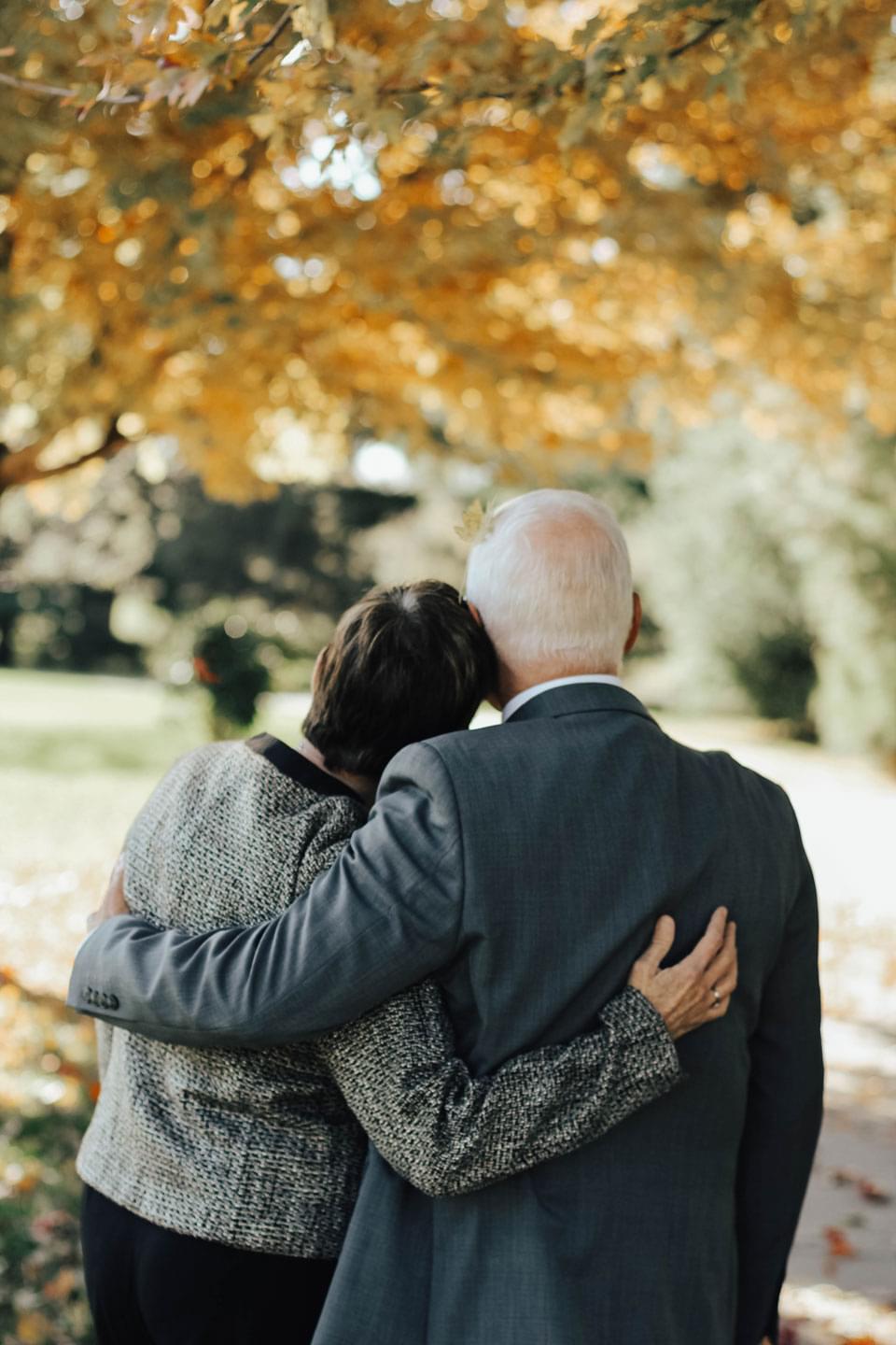Altes Ehepaar umarmt sich trauernd bei Beerdigung